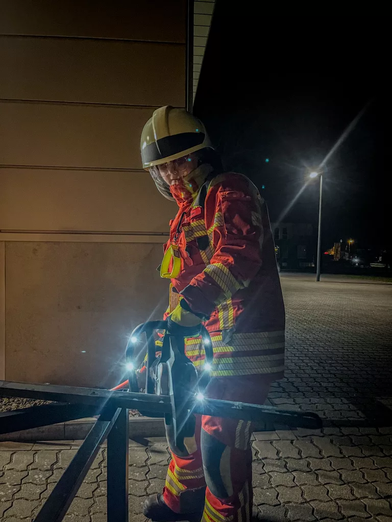 Feuerwehrfrau zertrennt Metallgestell mit einer hydraulischen Rettungsschere